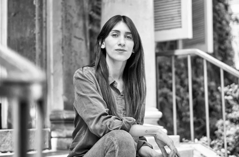 Foto en blanco y negro de la autora Catalina Infante, autora de La grieta, sentada en unas escaleras.